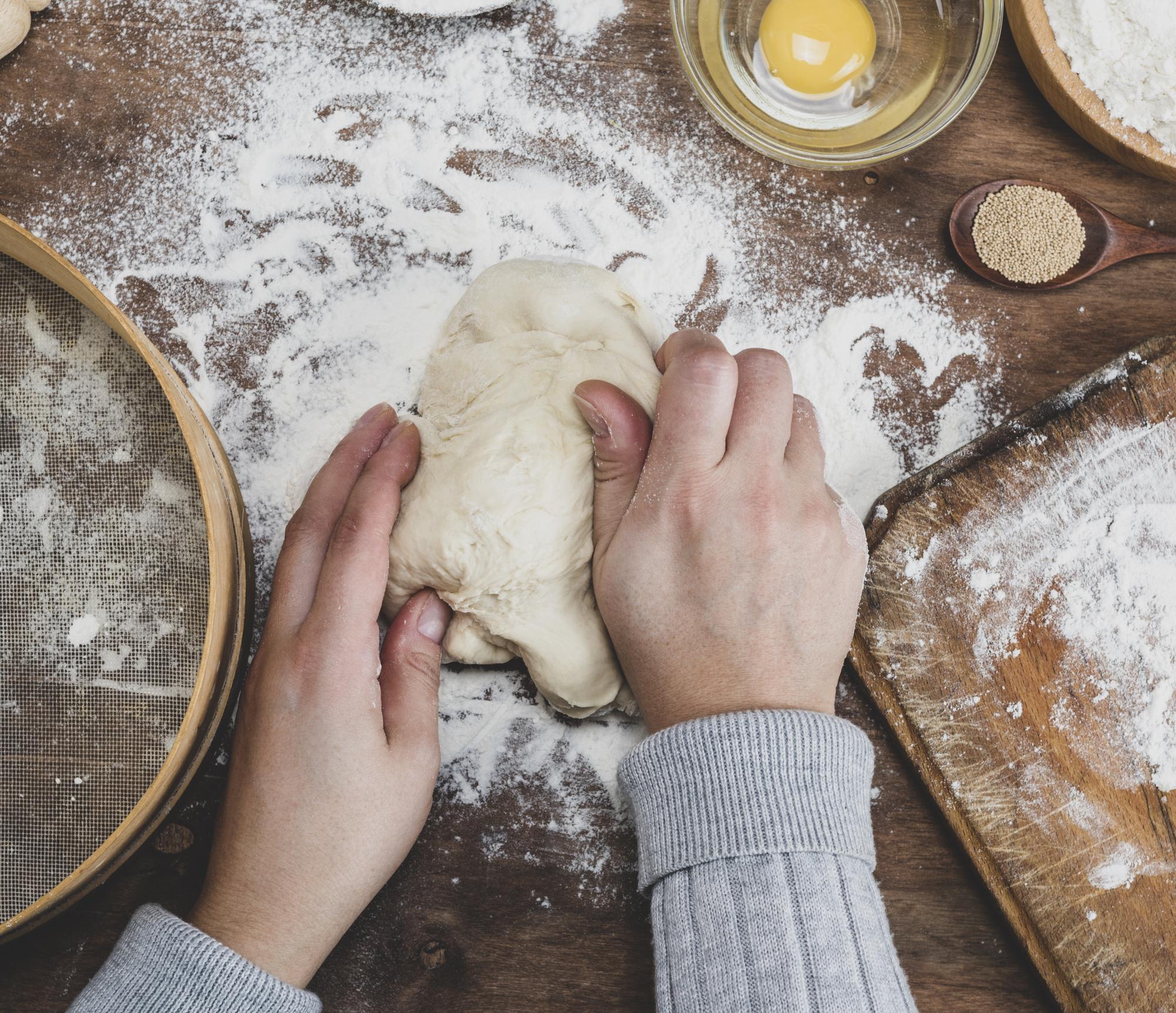 Close-up hands shaping dough on wooden board